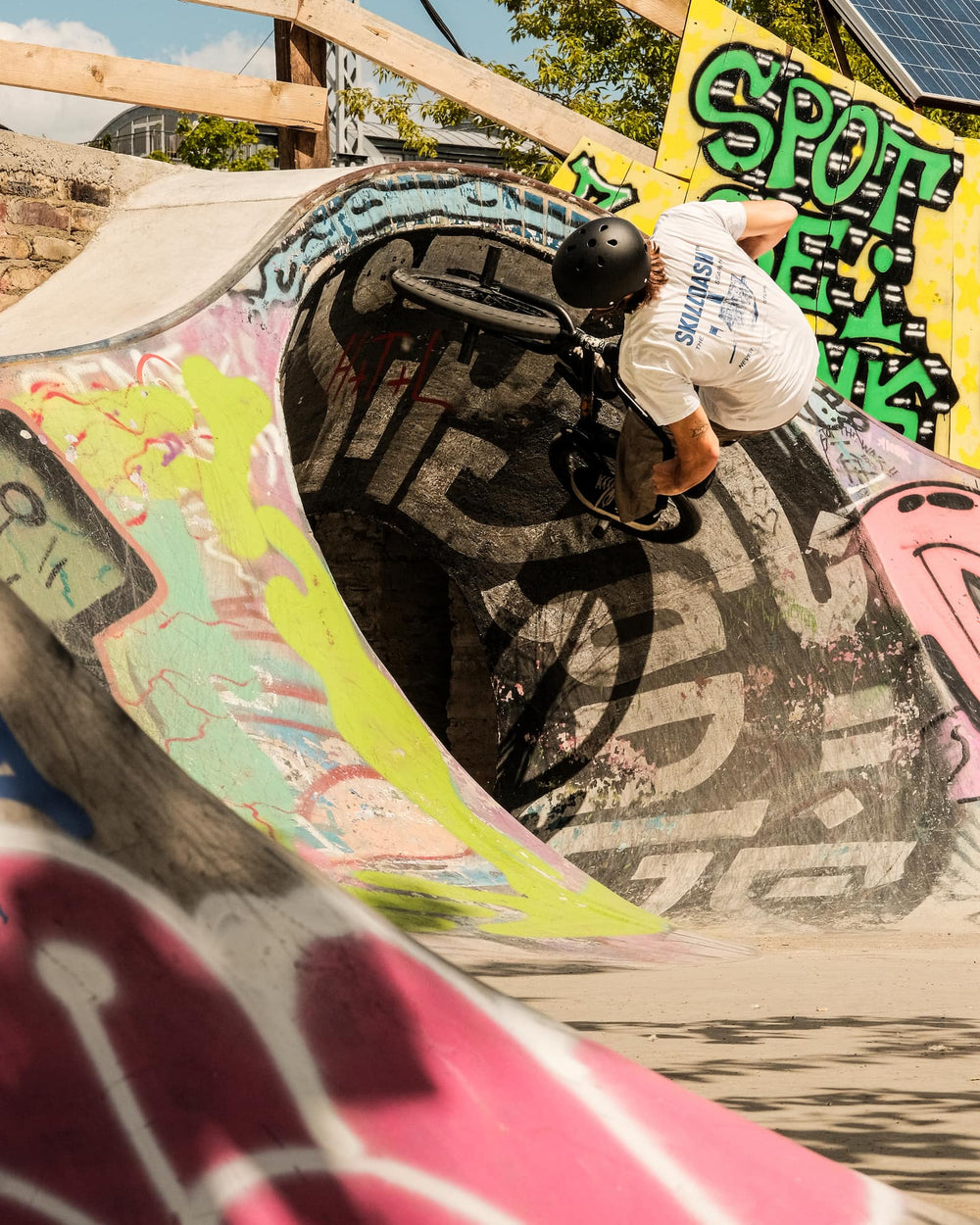 A person performing a BMX trick in a closed loop feature at a skatepark 